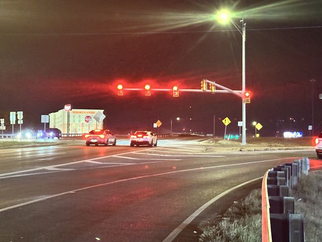 Traffic signals over a divided boulevard at night